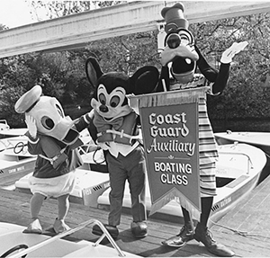 Donald Duck, Mickey Mouse and Goofy hold a banner for Coast Guard Auxiliary Boating Class